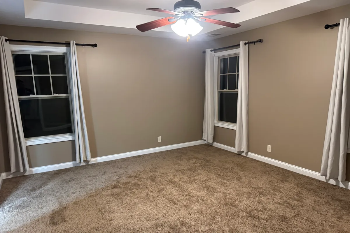 Empty living room with new carpet, fresh paint and a tray ceiling, cleared out and ready for the next tenant to move in.