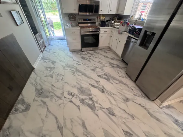 Kitchen with a new marble-look tile floor, stainless steel appliances and cabinetry above.