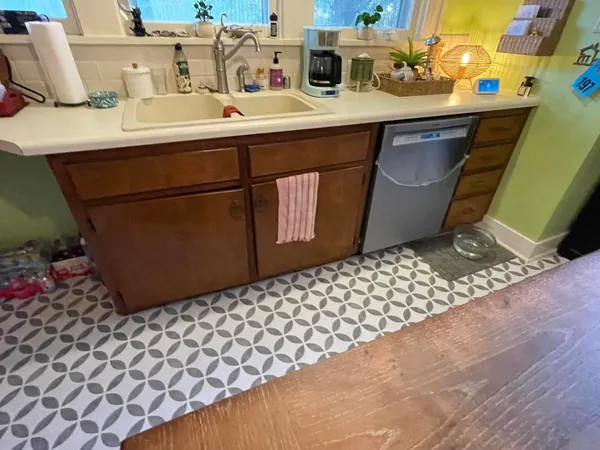 Sink run of kitchen cabinets in the original wood stain under a cast sink and window, doors closed and hardware original.