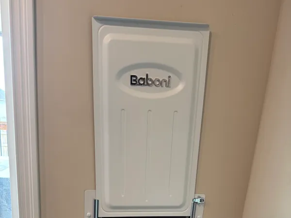 The inside of the same pet door, trimmed square against the interior wall with the sliding metal security panel raised above it and the baseboard cut in around the frame.