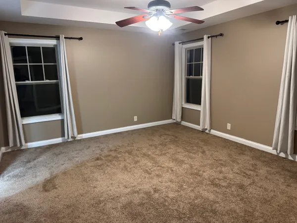 Empty living room with new carpet, fresh paint and a tray ceiling, cleared out and ready for the next tenant to move in.
